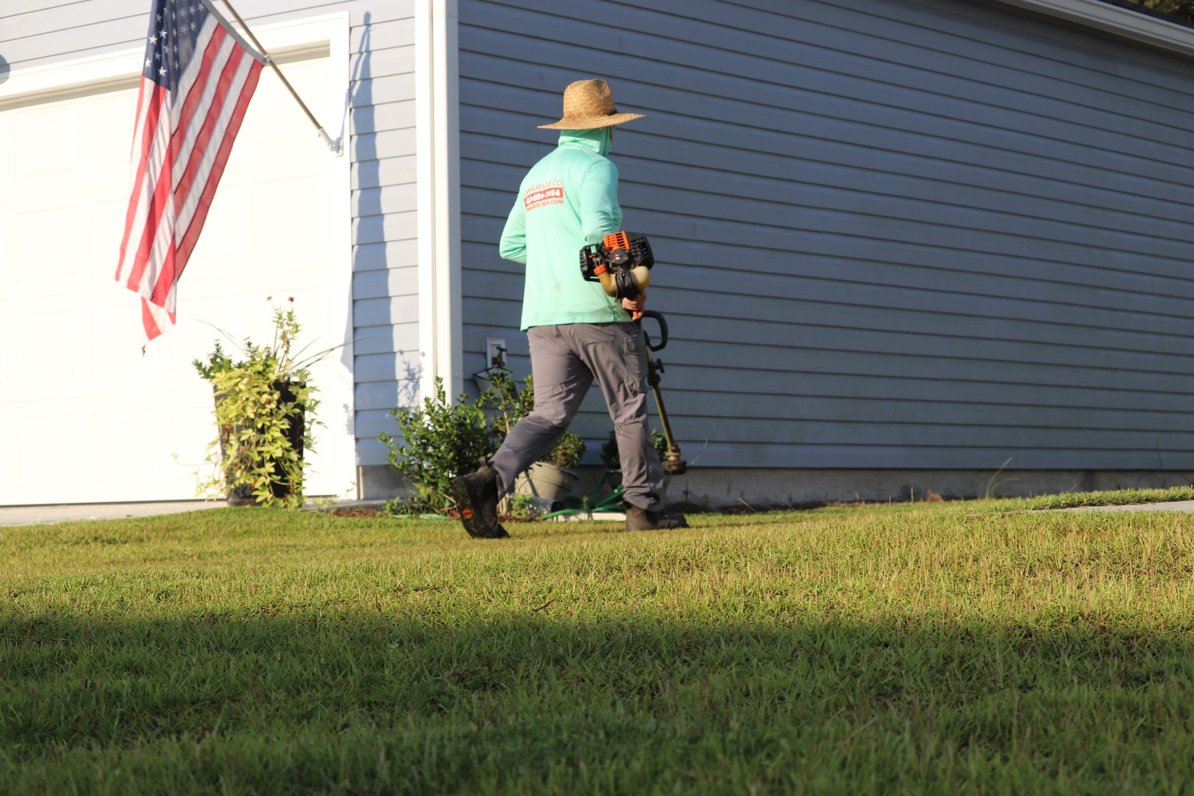 Lawn Rescue crew member working with an American flag flying nearby