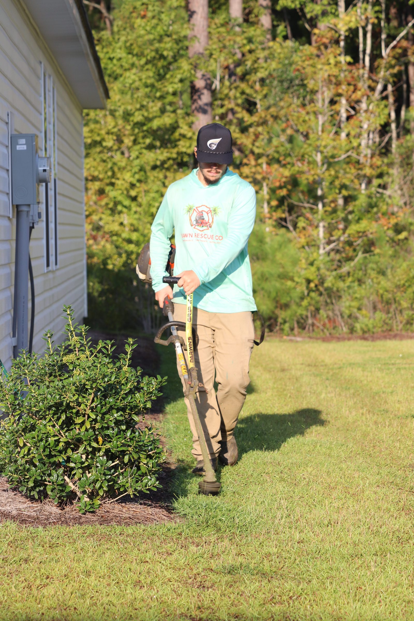 Crew member string-trimming around a home